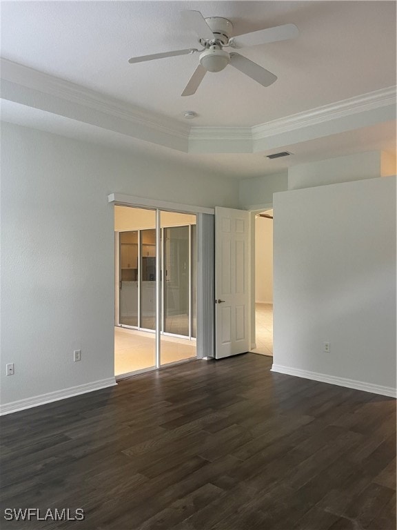 unfurnished room featuring ceiling fan, a tray ceiling, dark hardwood / wood-style floors, and crown molding