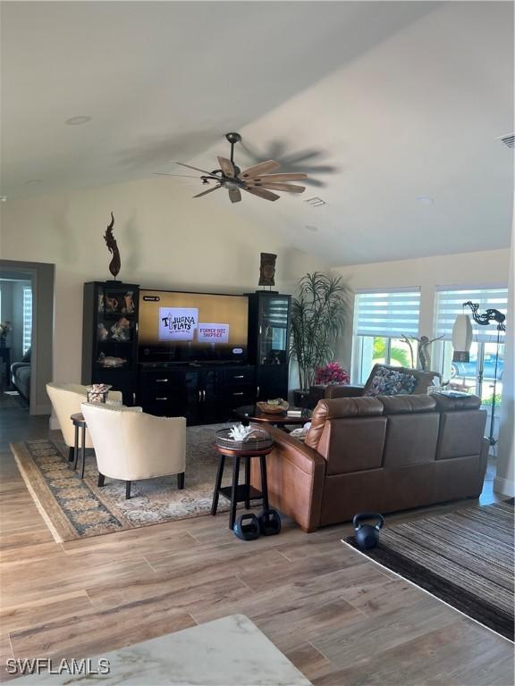 living room with hardwood / wood-style floors, ceiling fan, and lofted ceiling