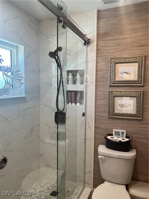 bathroom with toilet and an enclosed shower