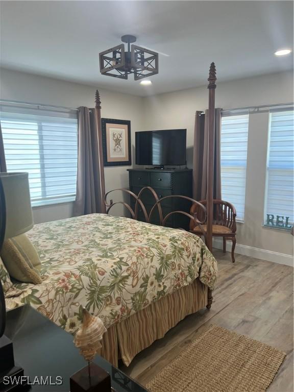 bedroom with multiple windows, light hardwood / wood-style flooring, and a chandelier