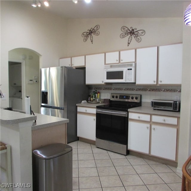 kitchen featuring stainless steel appliances, white cabinets, high vaulted ceiling, decorative backsplash, and light tile patterned flooring