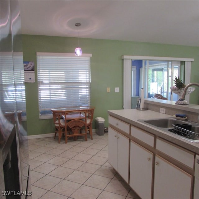 kitchen featuring light tile patterned flooring, sink, white cabinetry, and hanging light fixtures