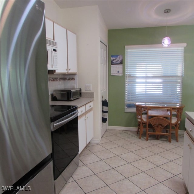 kitchen featuring appliances with stainless steel finishes, decorative light fixtures, white cabinetry, and light tile patterned flooring