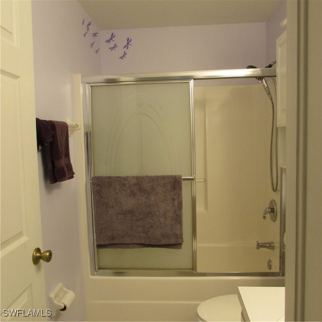 bathroom featuring combined bath / shower with glass door and toilet