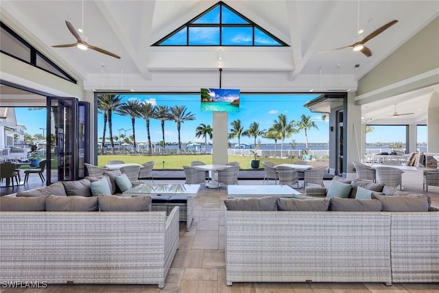 interior space featuring stone tile floors, beamed ceiling, ceiling fan, high vaulted ceiling, and plenty of natural light