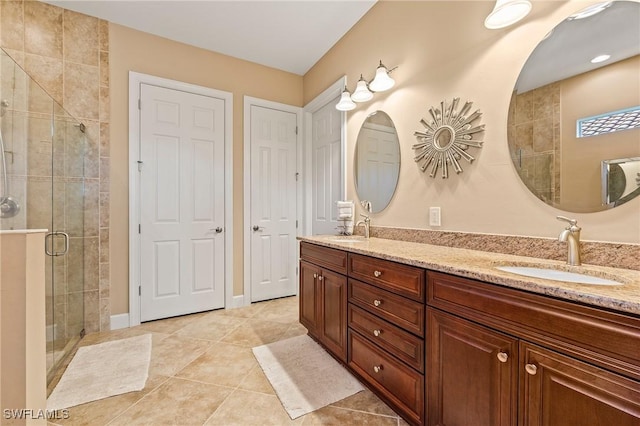 bathroom featuring double vanity, a sink, tile patterned flooring, and a stall shower
