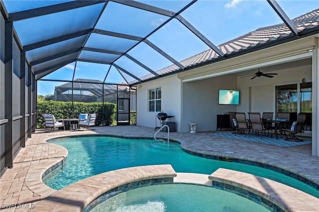 view of pool featuring outdoor dining space, a pool with connected hot tub, ceiling fan, a patio area, and glass enclosure