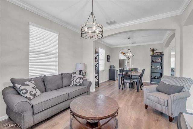 living room with hardwood / wood-style flooring, ornamental molding, and an inviting chandelier