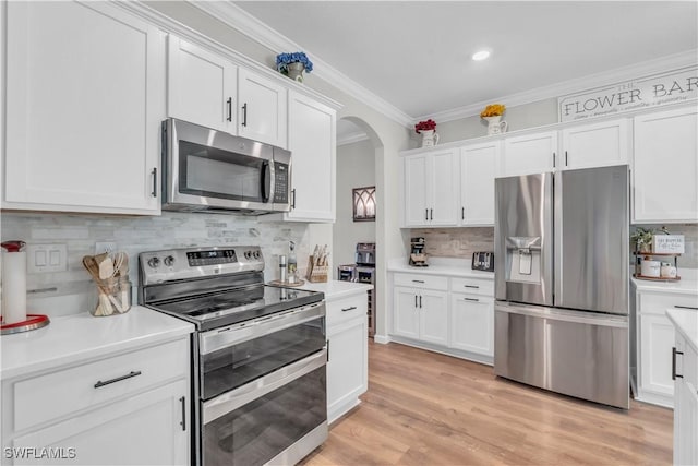 kitchen with white cabinetry, crown molding, appliances with stainless steel finishes, and light hardwood / wood-style flooring