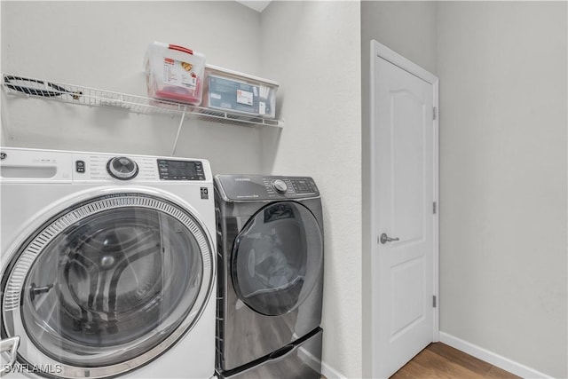 clothes washing area with wood-type flooring and independent washer and dryer