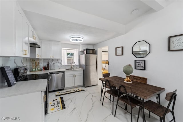 kitchen with tasteful backsplash, sink, white cabinets, and appliances with stainless steel finishes