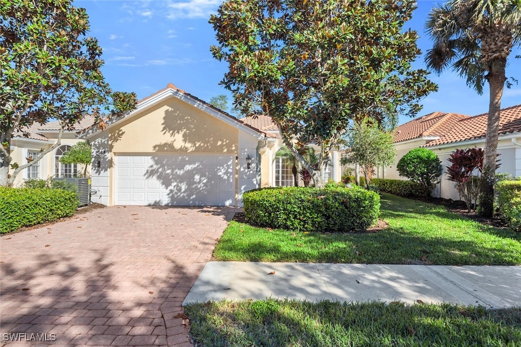 view of front of property with a garage, a front lawn, and cooling unit