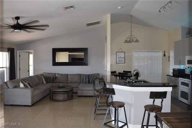 kitchen featuring a kitchen bar, kitchen peninsula, white appliances, sink, and lofted ceiling