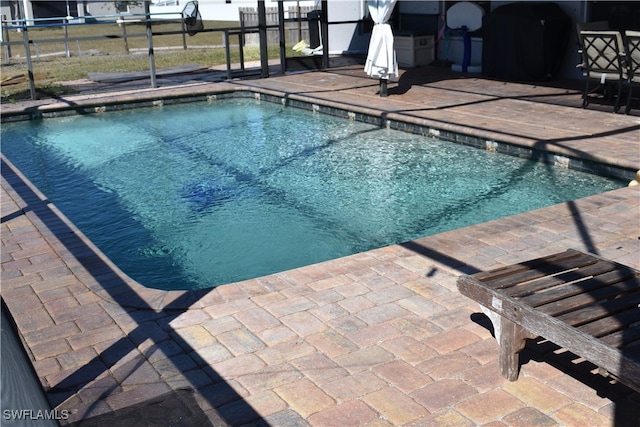 view of swimming pool featuring glass enclosure and a patio area