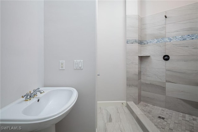 bathroom featuring tiled shower and sink