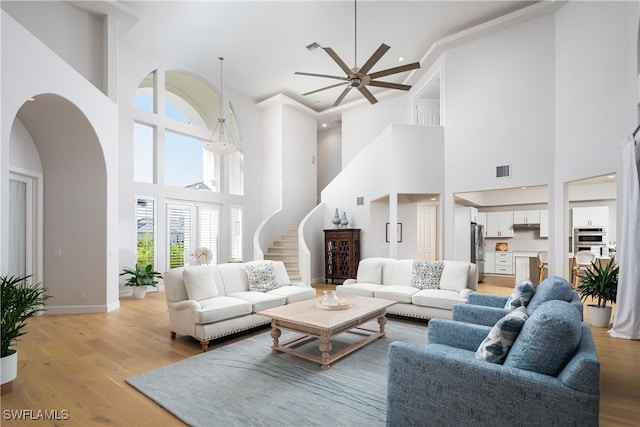 living room with ceiling fan, light hardwood / wood-style floors, and a high ceiling