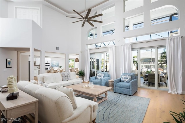 living room with a high ceiling, light hardwood / wood-style flooring, and ceiling fan