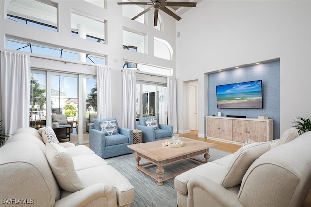 living room featuring wood-type flooring, a towering ceiling, and ceiling fan