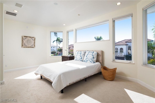 bedroom with light carpet and multiple windows