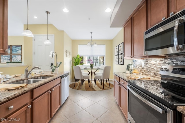 kitchen featuring pendant lighting, stainless steel appliances, light stone countertops, and sink