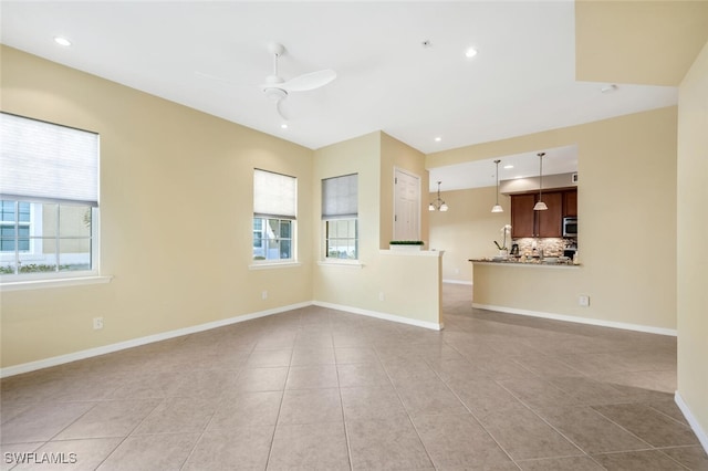 unfurnished living room featuring ceiling fan, light tile patterned flooring, and a wealth of natural light