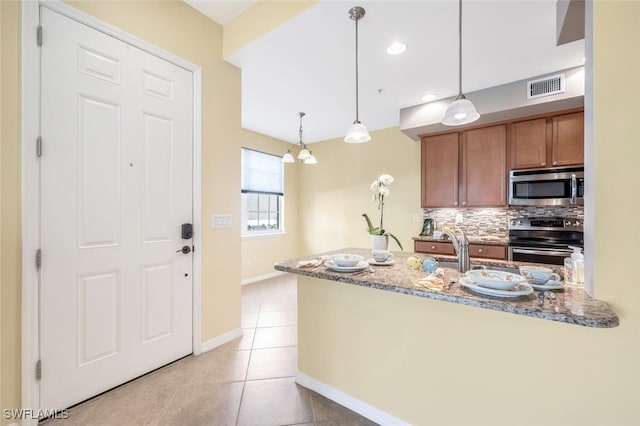 kitchen featuring light tile patterned floors, light stone countertops, hanging light fixtures, and appliances with stainless steel finishes