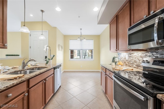 kitchen with sink, stainless steel appliances, light stone counters, pendant lighting, and light tile patterned floors