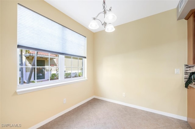 unfurnished room featuring a chandelier and light tile patterned flooring