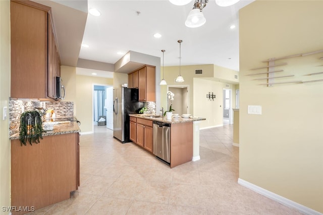 kitchen with kitchen peninsula, appliances with stainless steel finishes, tasteful backsplash, and hanging light fixtures