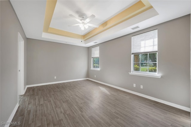 unfurnished room with hardwood / wood-style floors, ceiling fan, and a raised ceiling