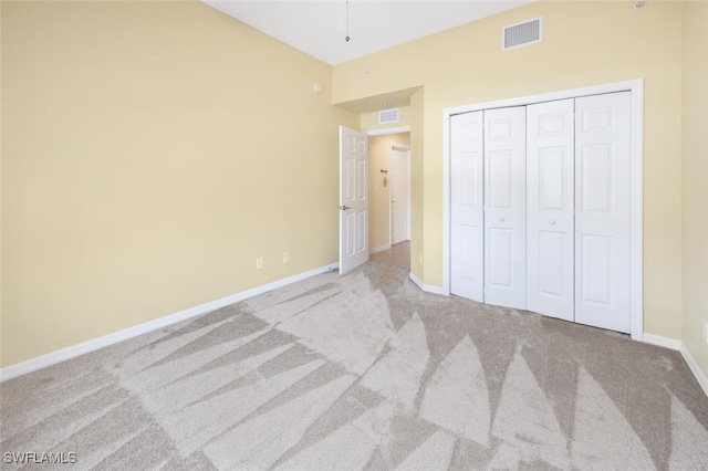 unfurnished bedroom featuring light colored carpet and a closet