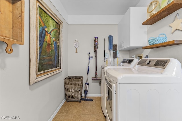 laundry room with light tile patterned flooring, cabinets, and washing machine and clothes dryer