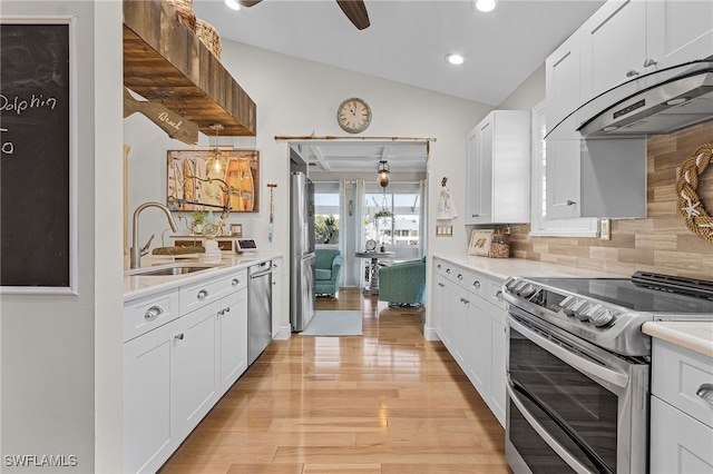 kitchen with appliances with stainless steel finishes, sink, light hardwood / wood-style flooring, white cabinetry, and lofted ceiling