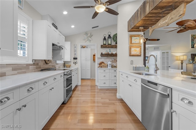 kitchen with stainless steel appliances, vaulted ceiling, sink, light hardwood / wood-style flooring, and white cabinets