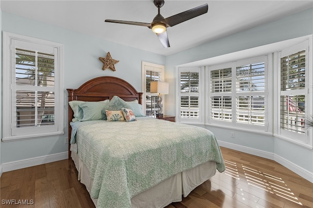 bedroom featuring multiple windows, wood-type flooring, and ceiling fan