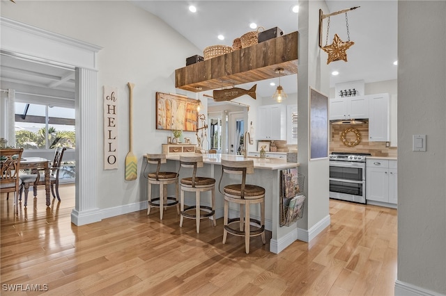 kitchen with white cabinetry, electric range, hanging light fixtures, a kitchen bar, and light wood-type flooring