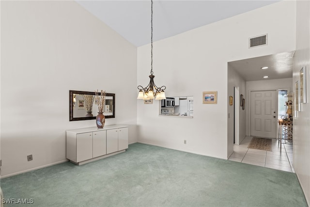 unfurnished dining area featuring light colored carpet, high vaulted ceiling, and a chandelier