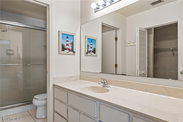 bathroom featuring tile patterned floors, a shower with door, vanity, and toilet