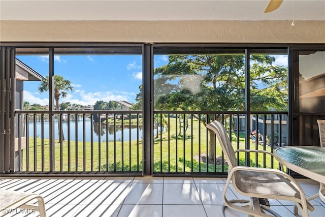 sunroom with plenty of natural light, ceiling fan, and a water view