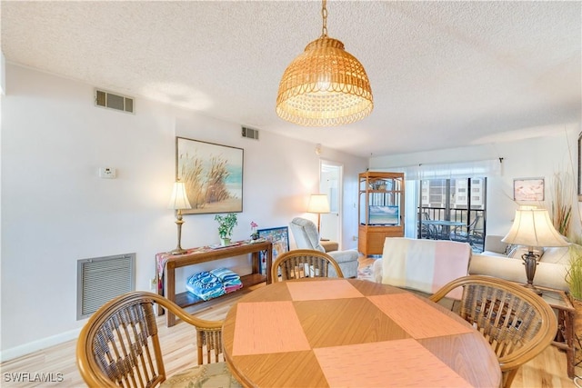 dining area with a textured ceiling and light hardwood / wood-style flooring