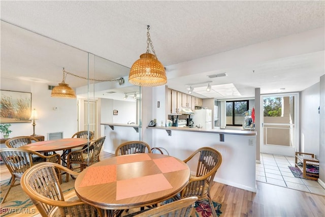 dining area featuring light wood-type flooring and a textured ceiling