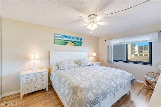 bedroom featuring a textured ceiling, light hardwood / wood-style floors, and ceiling fan