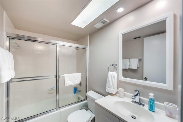 full bathroom featuring a skylight, toilet, vanity, and combined bath / shower with glass door