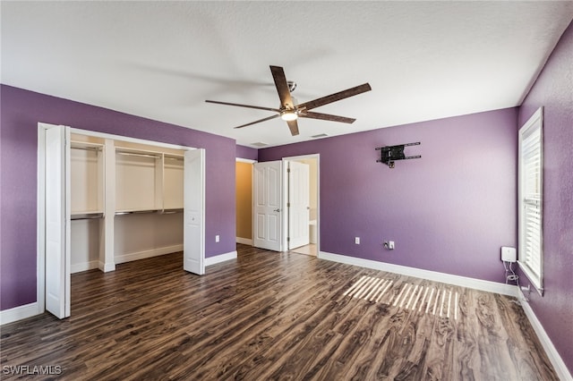 unfurnished bedroom with ceiling fan, a closet, and dark wood-type flooring