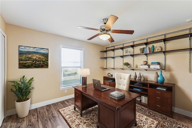 home office with dark hardwood / wood-style flooring and ceiling fan