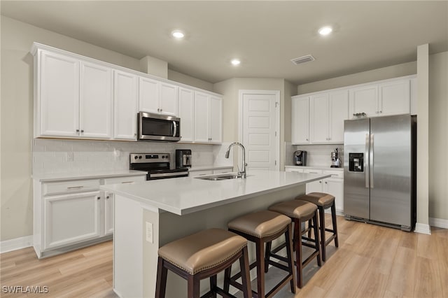 kitchen with white cabinets, sink, appliances with stainless steel finishes, and an island with sink