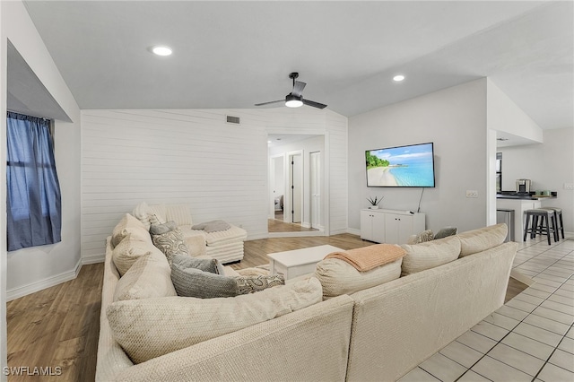 living room featuring ceiling fan, light hardwood / wood-style flooring, and vaulted ceiling