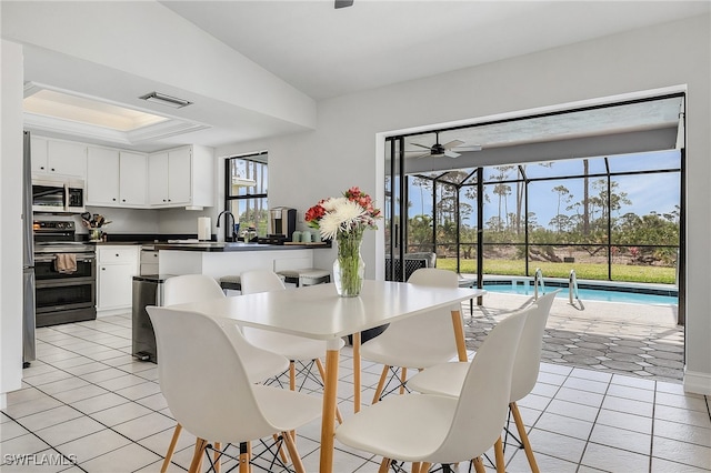 tiled dining space featuring ceiling fan and sink