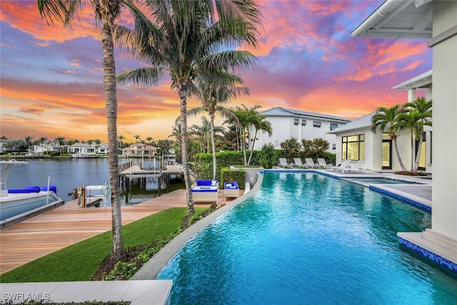 pool at dusk with a water view, a patio, and a boat dock