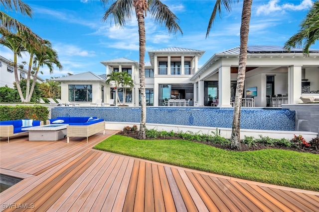 back of house with a wooden deck, a yard, and an outdoor living space with a fire pit